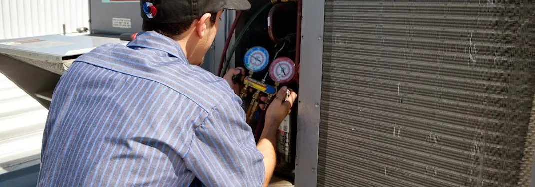 HVAC technician servicing a condenser unit in Oswego